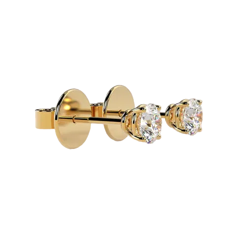 A pair of gold stud earrings with oval clear gemstones in a three-prong setting, shown on a plain beige background.