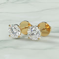Gold earrings with clear gemstones on a beige background