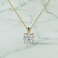 Gold necklace with a round diamond pendant on a beige background