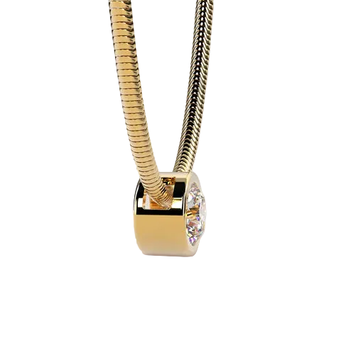 A gold snake chain necklace with a polished gold cylindrical pendant featuring a clear round gemstone, set against a solid light beige background.