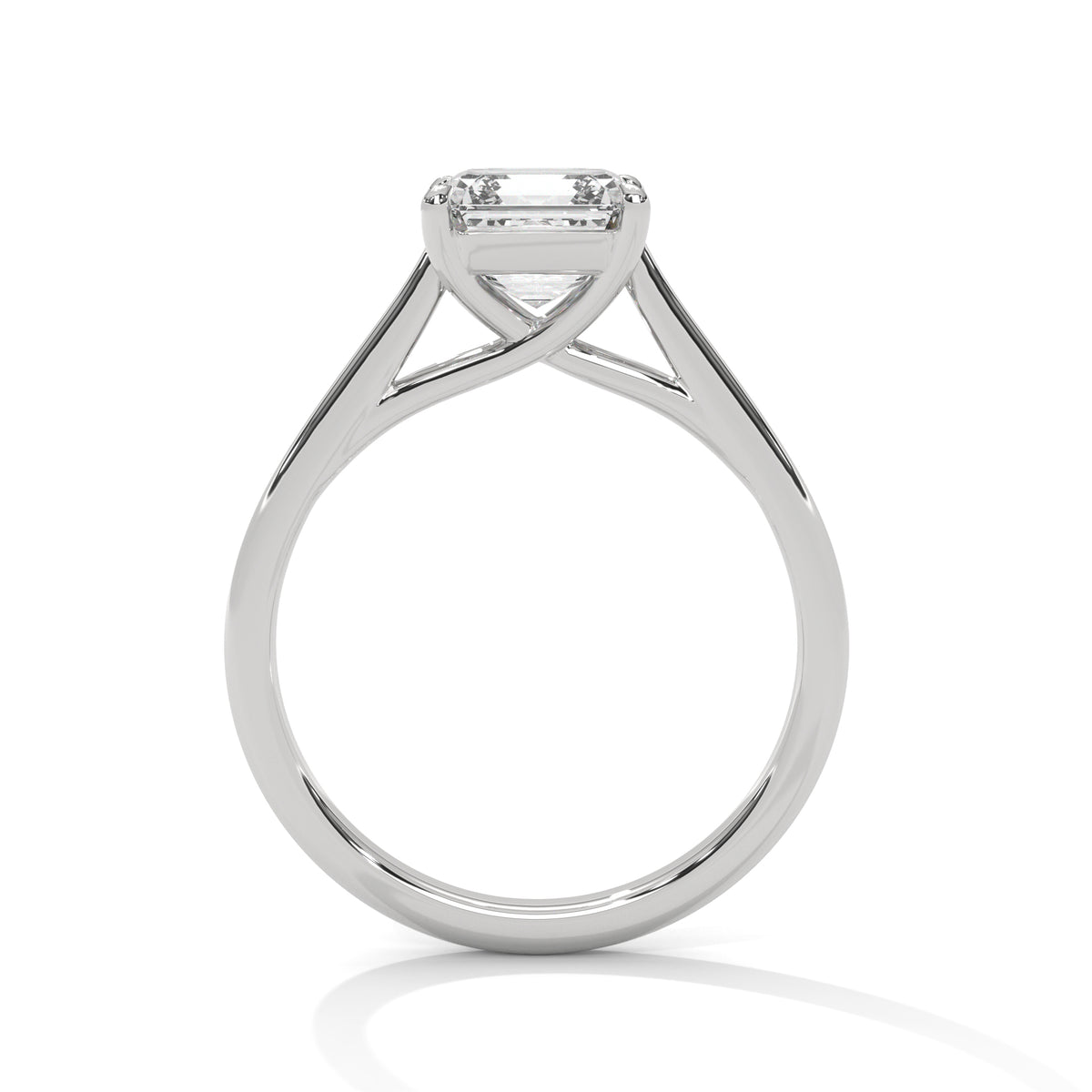 A silver-toned solitaire engagement ring with a rectangular clear gemstone in a four-prong setting, shown on a clean white background with a soft reflection below.