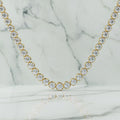Gold necklace with clear gemstones on a beige background