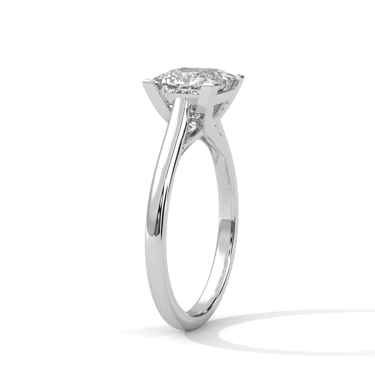 A classic solitaire engagement ring featuring a round brilliant-cut diamond set in a polished white gold or platinum four-prong setting, shown on a clean white background with a soft shadow.