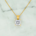Gold pendant necklace with a clear gemstone on a white background