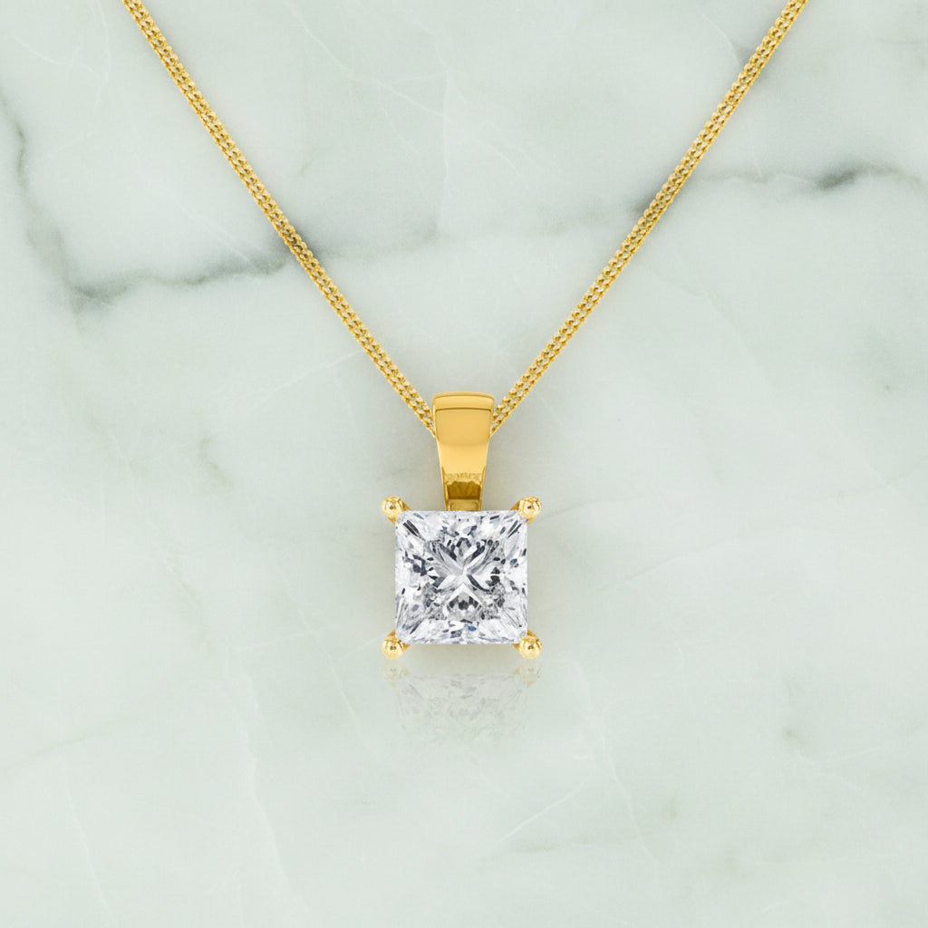 Gold pendant necklace with a clear gemstone on a white background