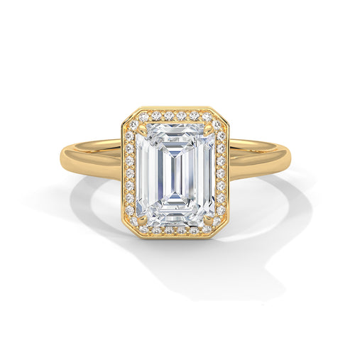 Gold ring with emerald-cut diamond and smaller diamonds on a white background