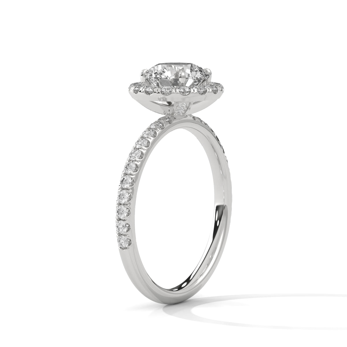 A silver-toned diamond ring with a round-cut center stone and a halo of smaller diamonds, set on a slim pavé band, shown on a white background.