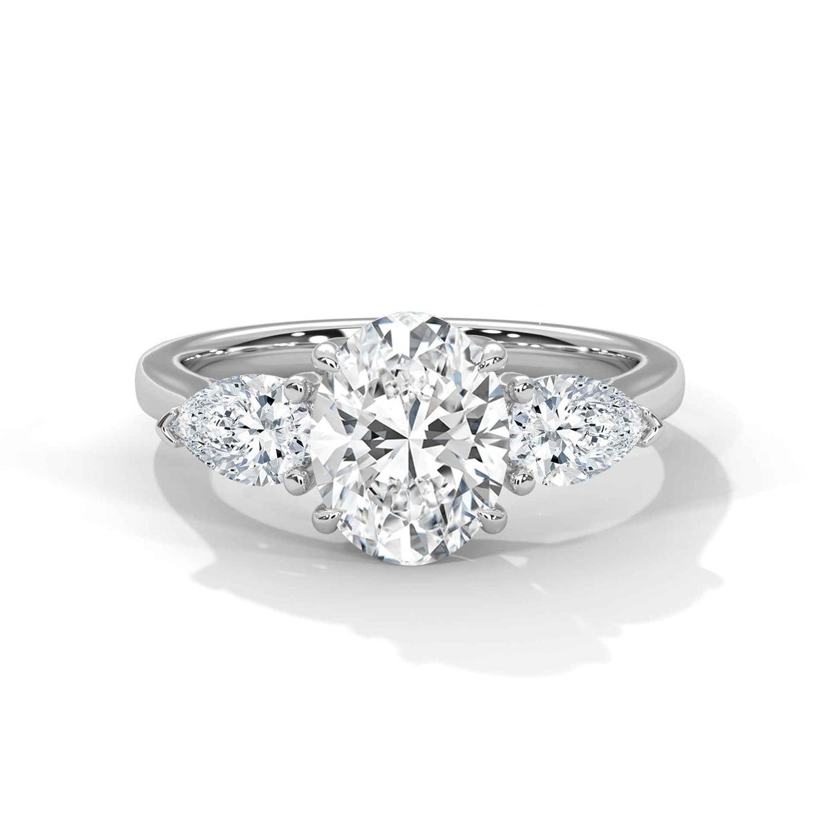 A three-stone diamond engagement ring with a large round center diamond and two smaller marquise-cut side diamonds on a polished silver-colored band, set against a clean white background with a soft shadow.