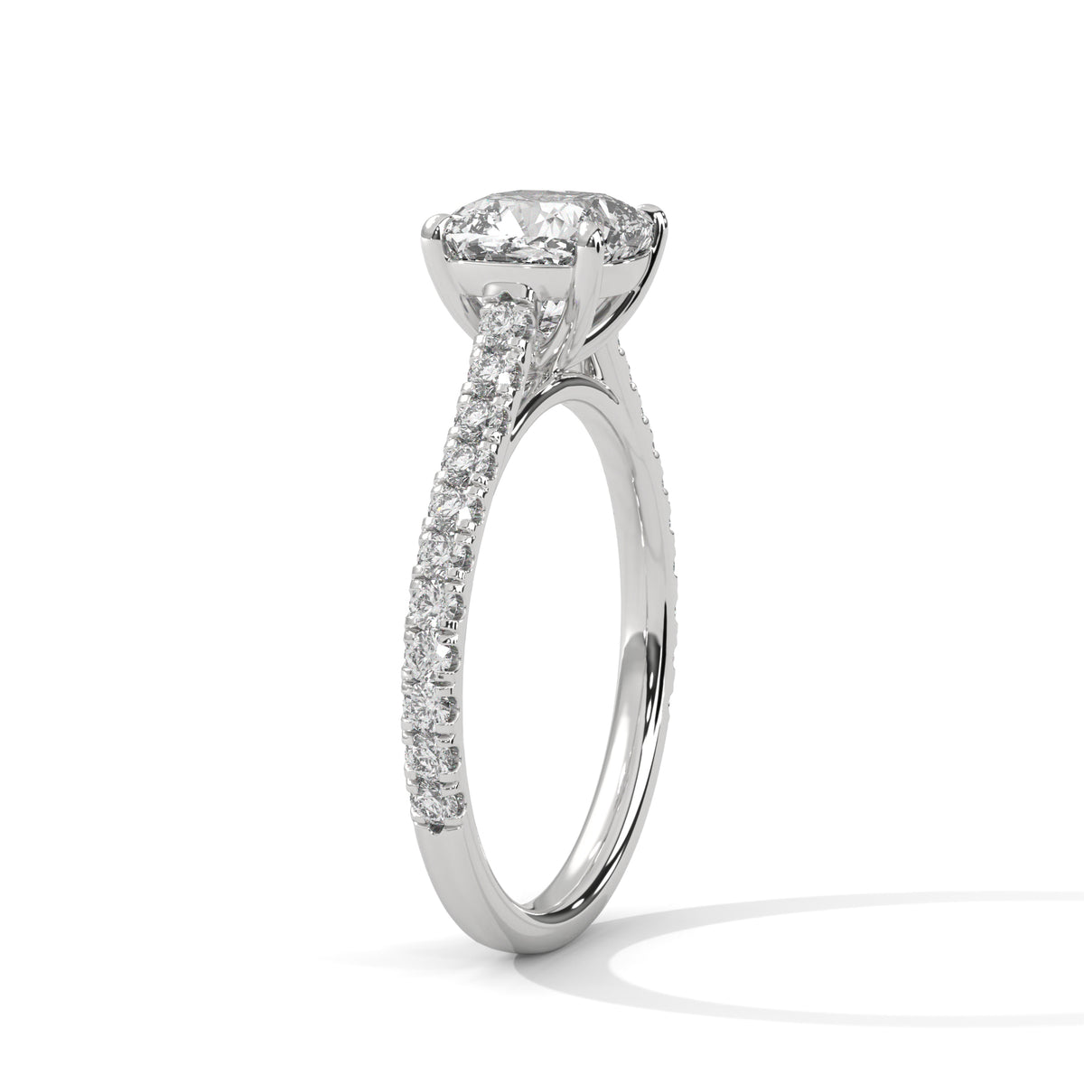 A silver-toned solitaire engagement ring featuring a round brilliant-cut diamond center stone and a pavé-set diamond band, shown on a clean white background.