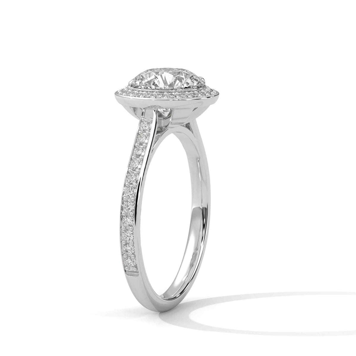 A silver-toned diamond ring with a round-cut center stone and a halo of smaller diamonds, set on a slim pavé-set band, shown on a white background with a soft shadow.
