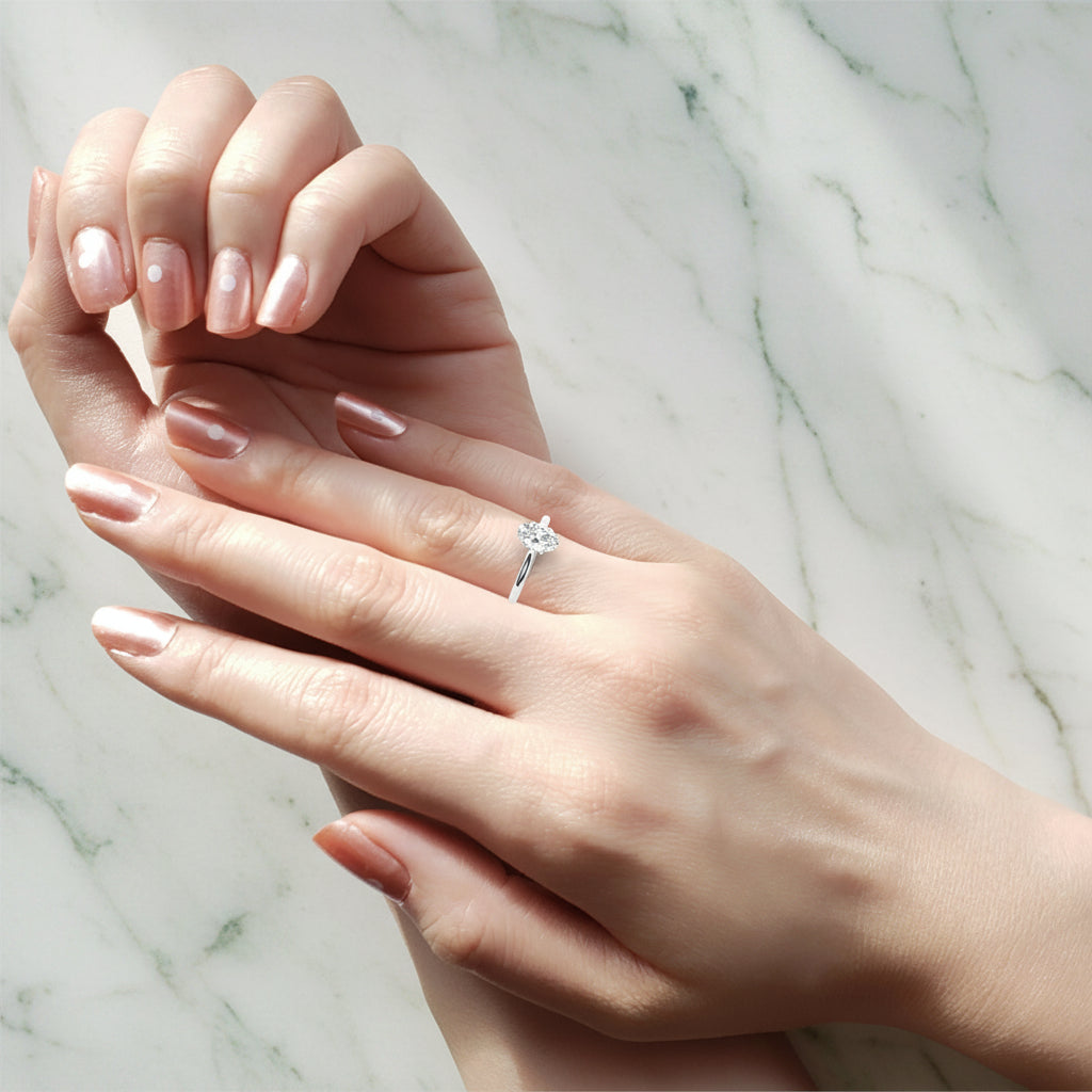 Close-up of a hand wearing a diamond ring on a neutral background