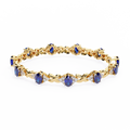 Gold bracelet with blue gemstones on a white background